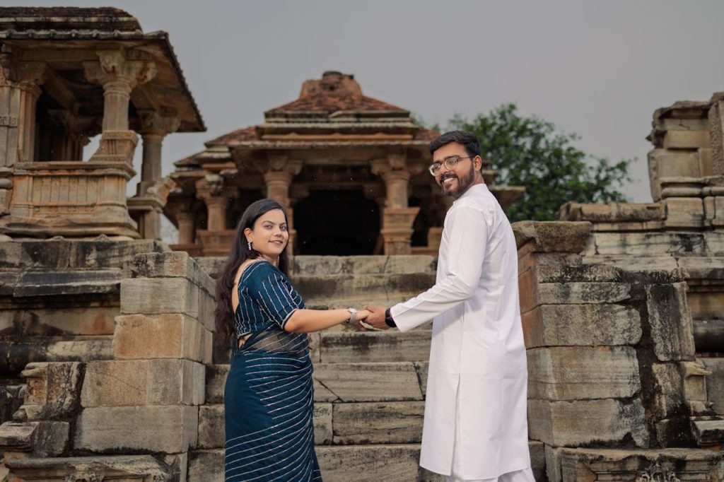 Smiling couple holding hands in traditional attire at a historic temple.