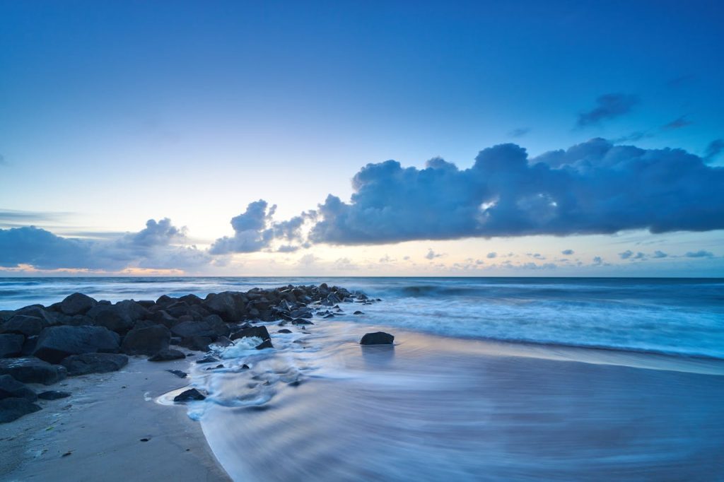 Beautiful sunset view of Lønstrup coastline with dramatic clouds and ocean waves.
